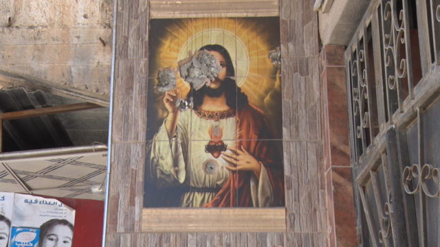 Above: Bullet holes mar a mural of Jesus on the facade of a local building, Qaraqosh, Iraq.